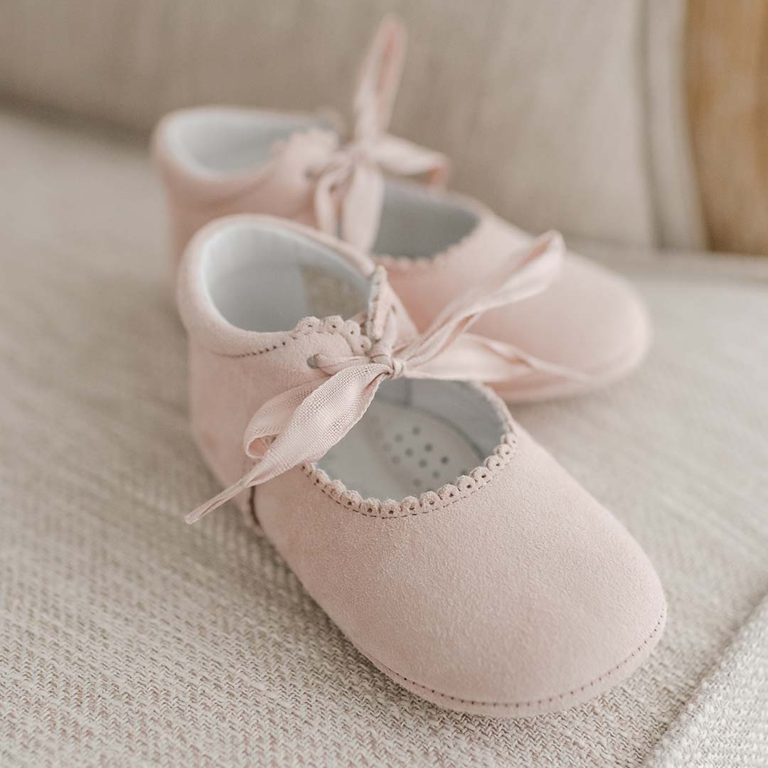 Flat lay of the Lola Suede Tie Mary Janes, crafted from soft rosy pink suede with scalloped edge detailing and finished with a delicate cotton ribbon tie.