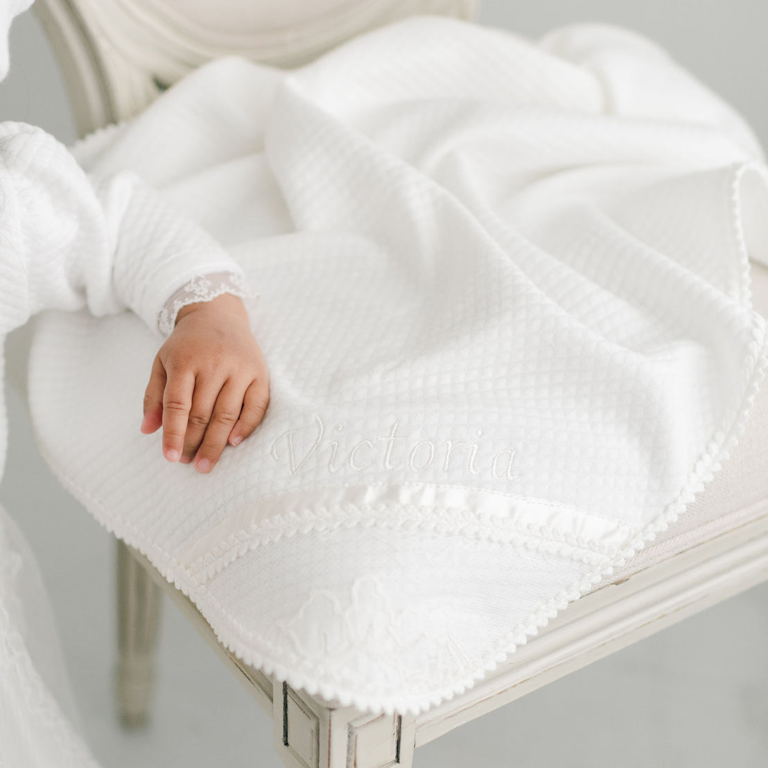 Closeup photograph of the Victoria baptism blanket, embroidered with the name Victoria in the corner. 