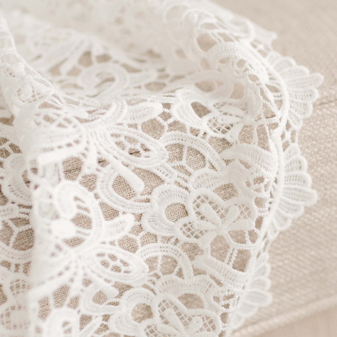 Close up detail of the Lola Christening Gown's all-over lace overlay that is a part of the skirt. 