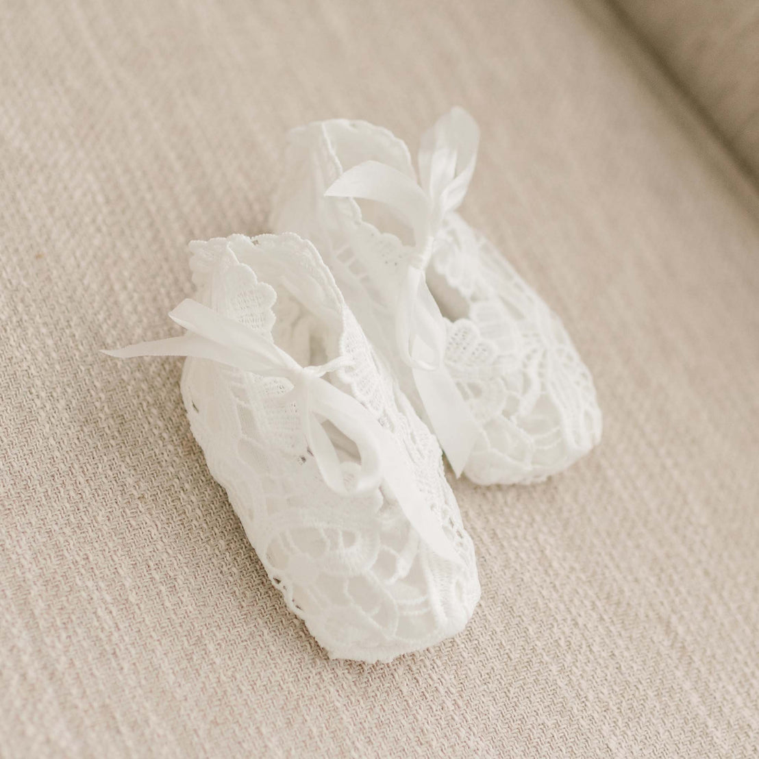 Flat lay of the Lola Booties, featuring light ivory lace and finished with silk bow ties.