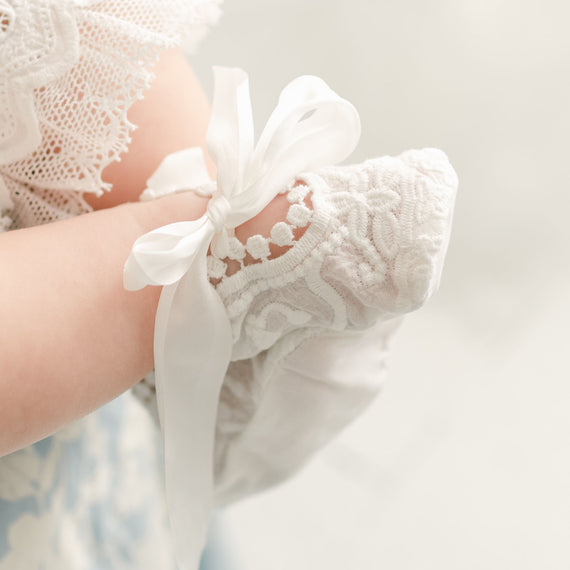 Detail of the Emily Booties made from a soft cotton lace in light ivory and adorned with a unique venice lace trim. Silk ribbon ties help keep the booties snug.