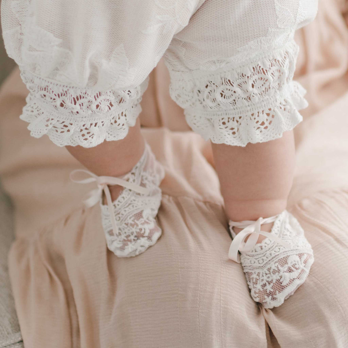 A close-up photo of a baby girl's legs wearing a Charlotte Romper and matching Charlotte Booties.