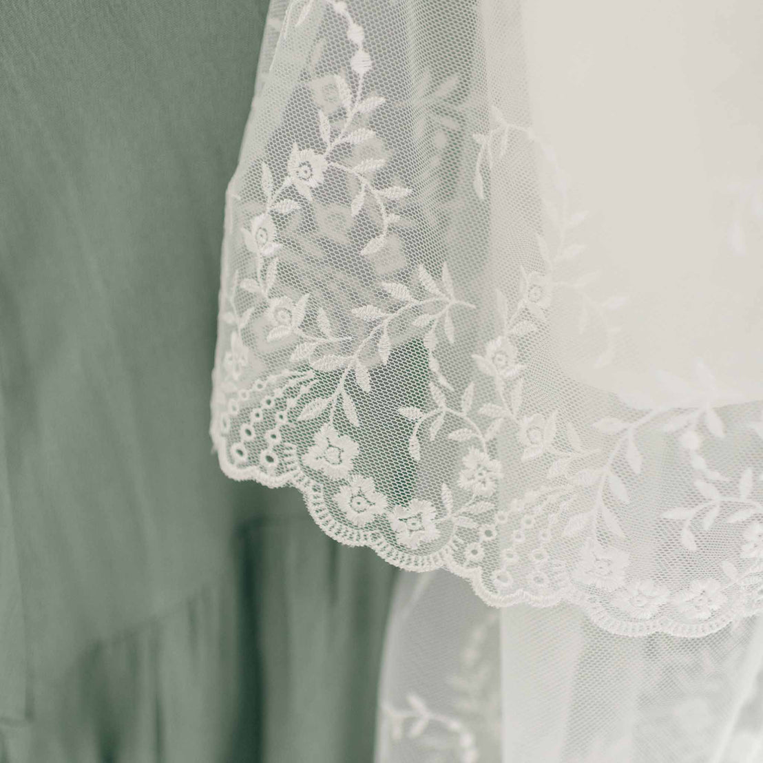 A close-up of the intricate floral embroidered netting lace on the skirt of the Ella Christening Gown.