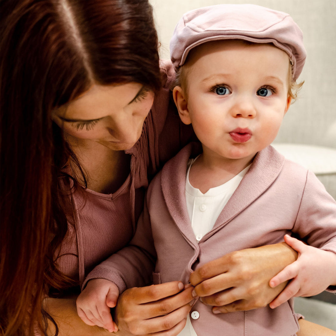 Baby boy sitting in mom's lap buttoning mauve cotton suit jacket