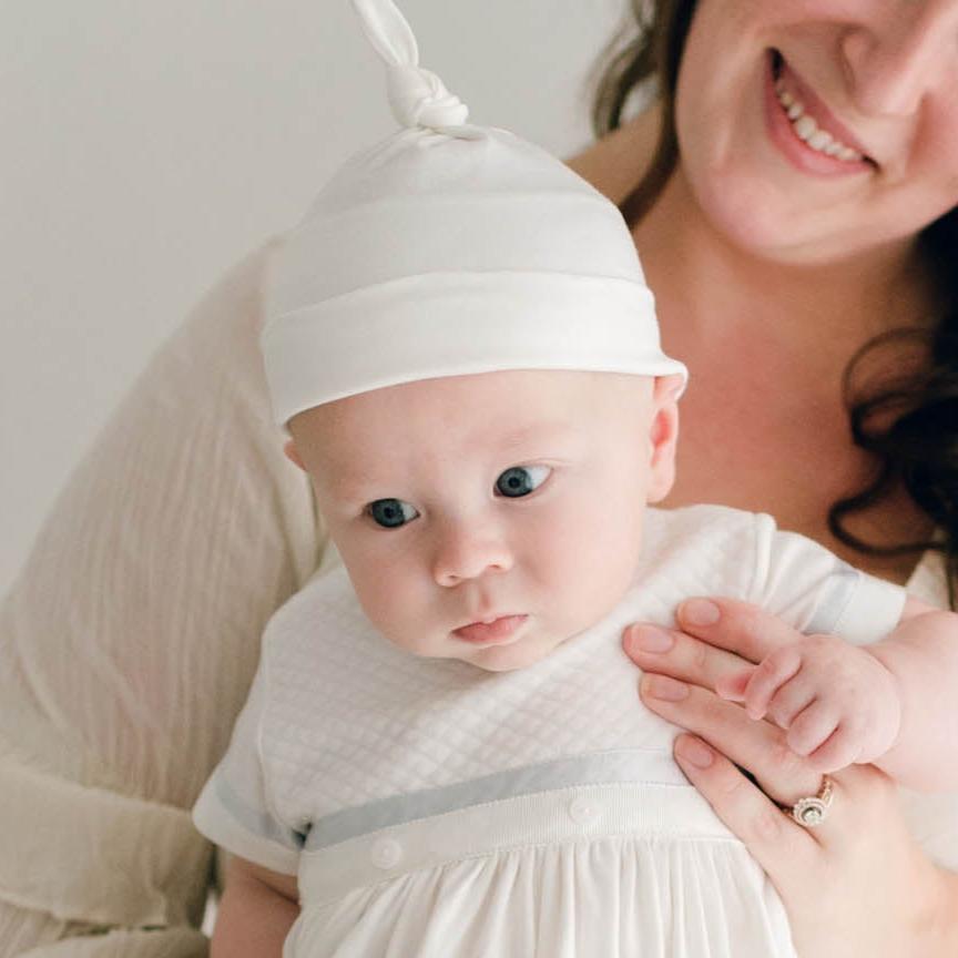 Baby boy being held by his mother. He is wearing the Owen Layette and Knot Cap