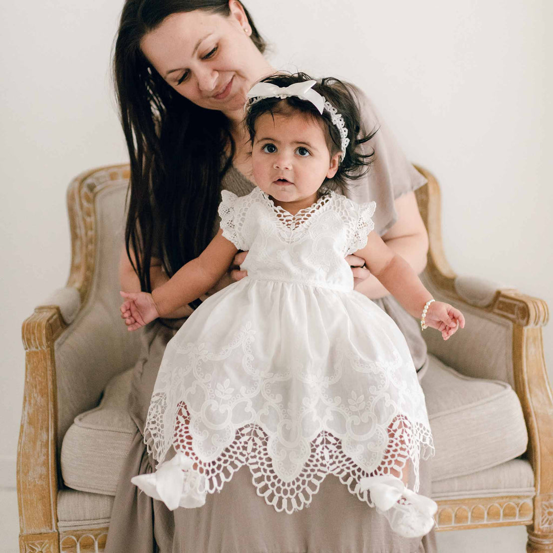 Baby wearing a christening romper dress and silk headband bow