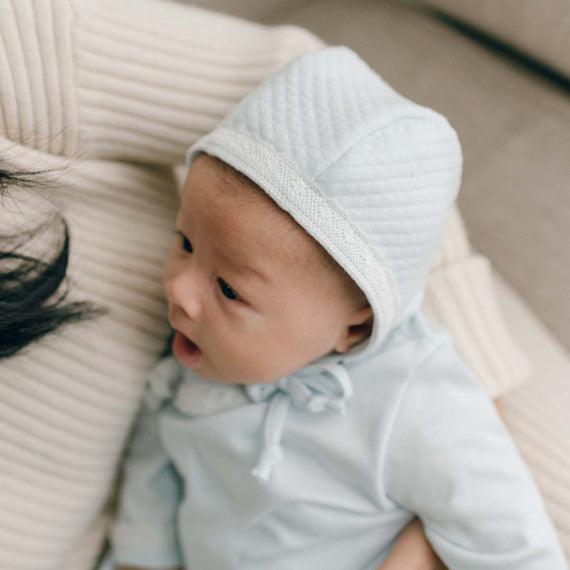 Baby boy yawning in blue quilted cotton newborn bonnet