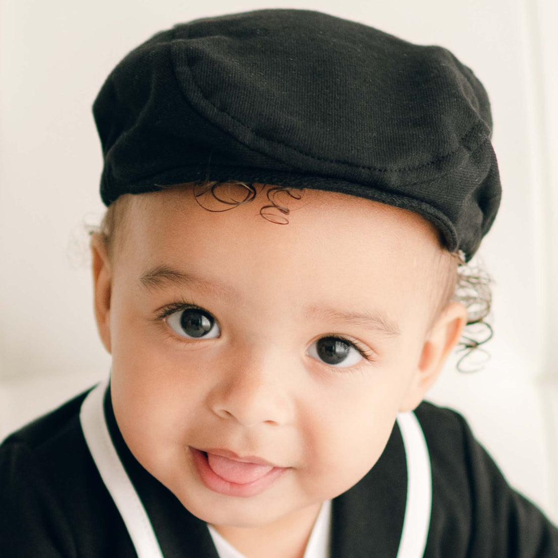 Baby boy wearing the black James Newsboy Cap made from 100% Black French Terry Cotton with a soft elastic back. 