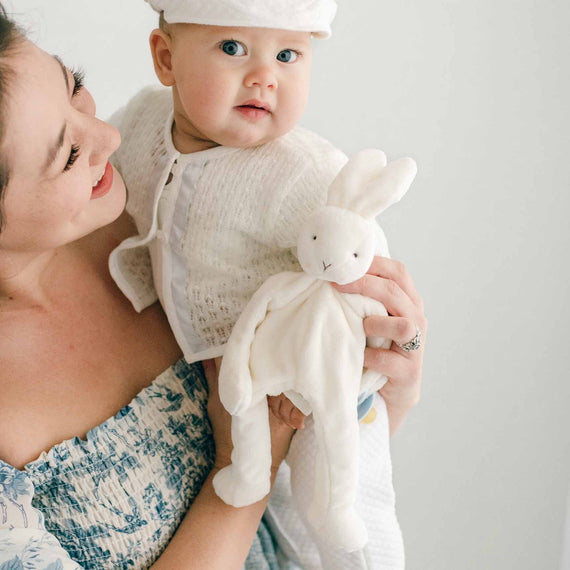 Baby boy being held by his mother and wearing the Owen 3-Piece Suit. He is also holding the Owen Silly Bunny Buddy & Baby Blue Pacifier