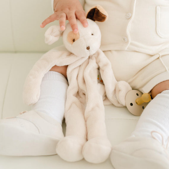 Photo of a baby holding the Braden Silly Puppy Buddy, a stuffed animal dog that can hold a pacifier