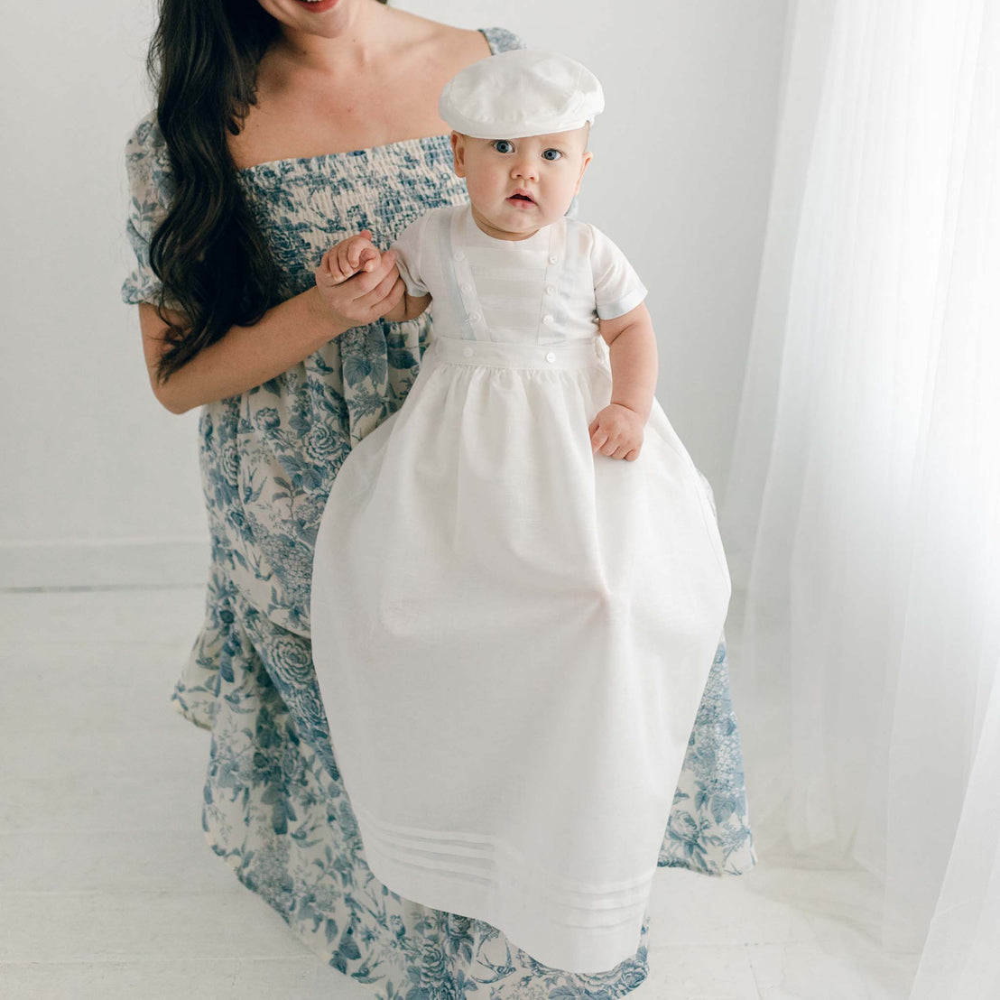 Baby boy sitting on his mother's lap. He is wearing the Owen Convertible Romper and Skirt Set.