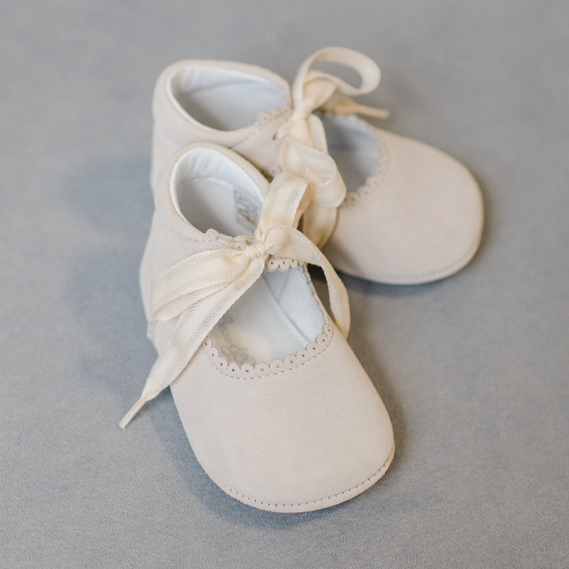 Flat lay photo showcasing the tan Emily Suede Tie Mary Janes. Shoes are made with a soft suede with tie detail closure.