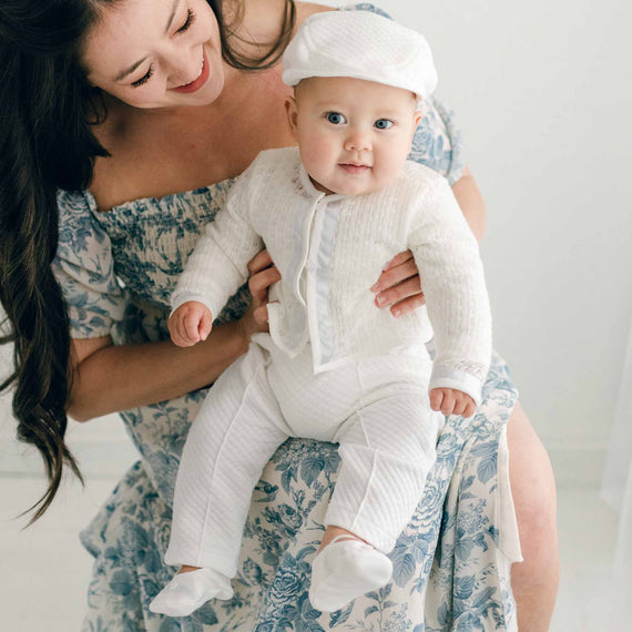 Baby boy sitting on the lap of his mother. He is wearing the Owen 3-Piece Suit, including the sweater, pants, and onesie