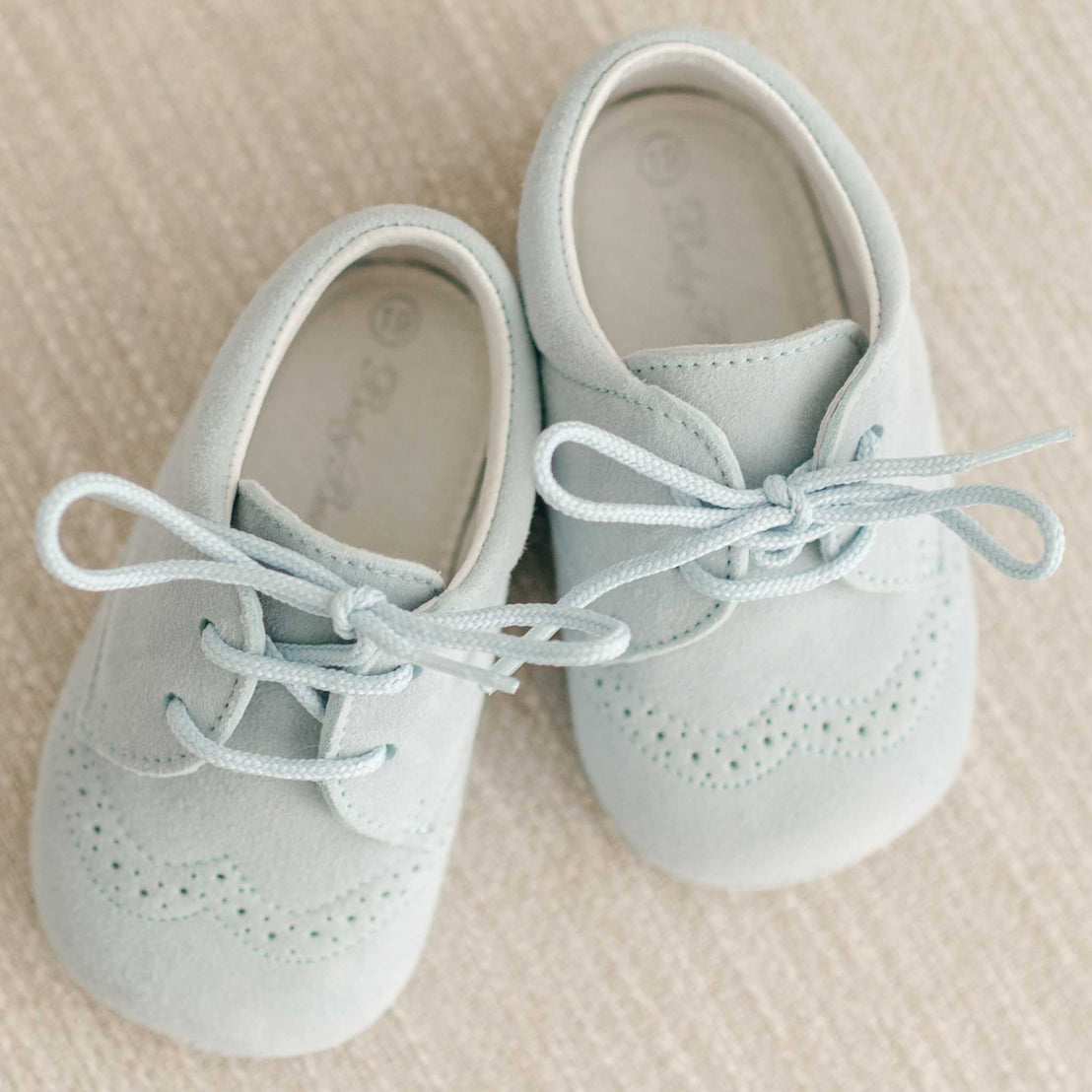 Flat lay of the Harrison Suede Shoes that are made with a super soft, light blue suede with detailed edging