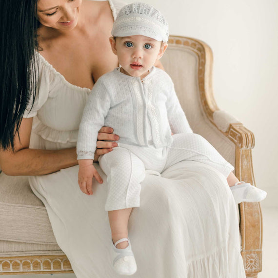 Baby boy sitting on his mother's lap. He is wearing the Harrison 3-piece suit with a blue knit sweater and matching hat 