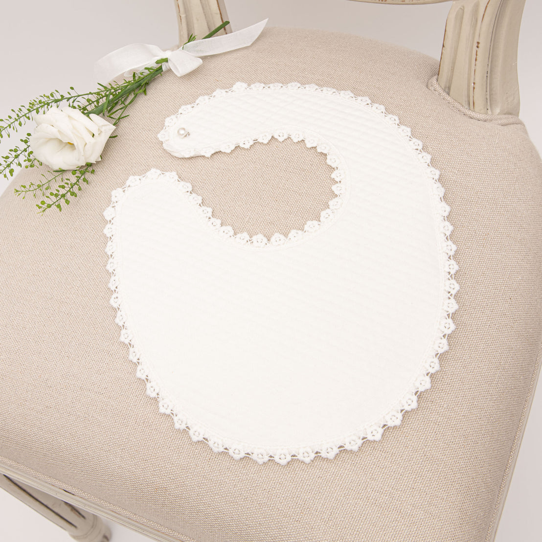 Photo of the Poppy baptism bib on chair.