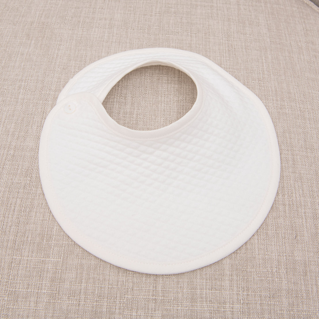 The Rowan baptism bib flat lay on chair.