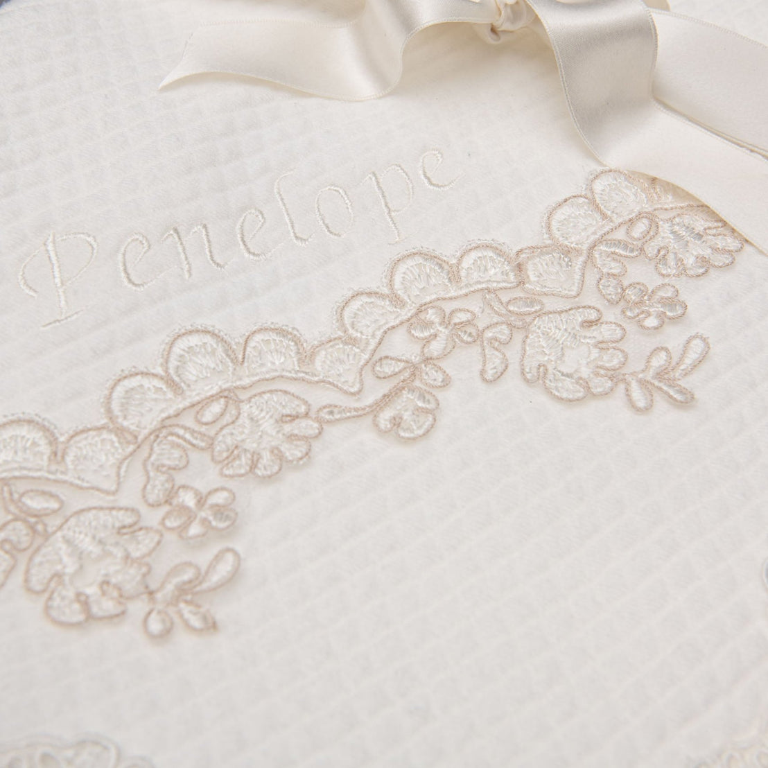 Close up detail of lace embroidery on the Penelope personalized baptism blanket.