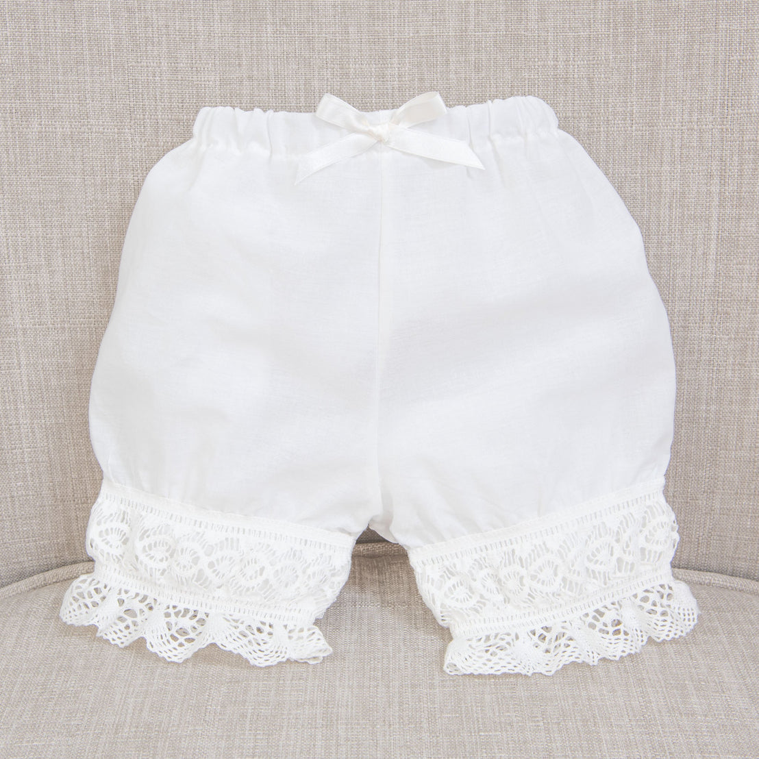 Isabella bloomers with lace trim and a bow, displayed against a textured gray background.