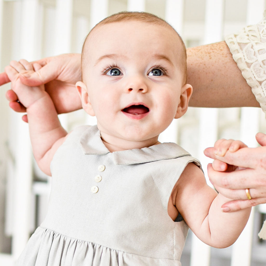 Close detail of baby boy wearing the Grayson Linen Romper. Detail shows pointed collar and button detail on the front.