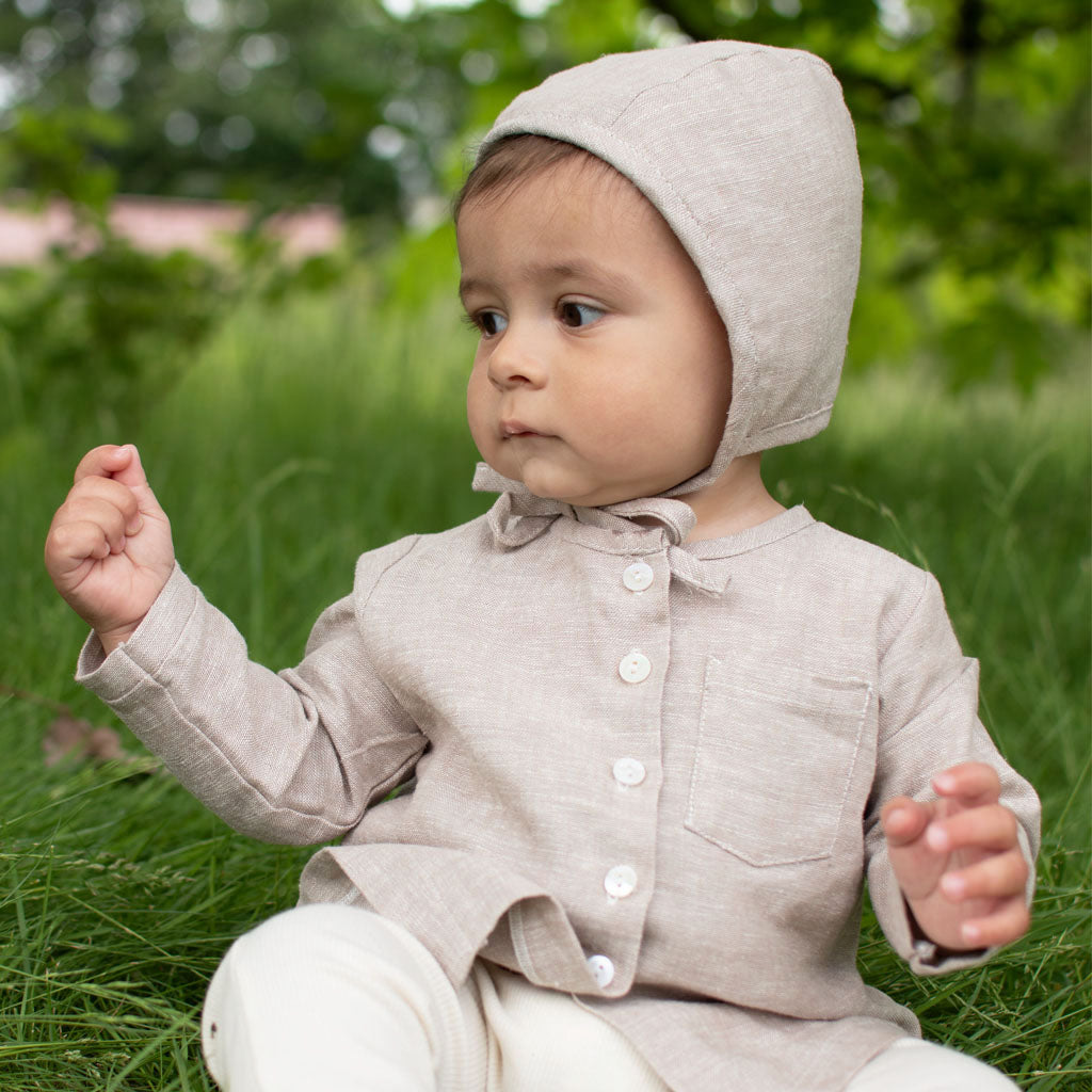 Baby boy wearing the sand colored Silas Linen Bonnet