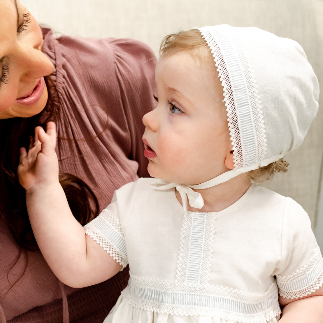 Baby boy with mom dressed in a traditional boys linen baptism gown and bonnet.