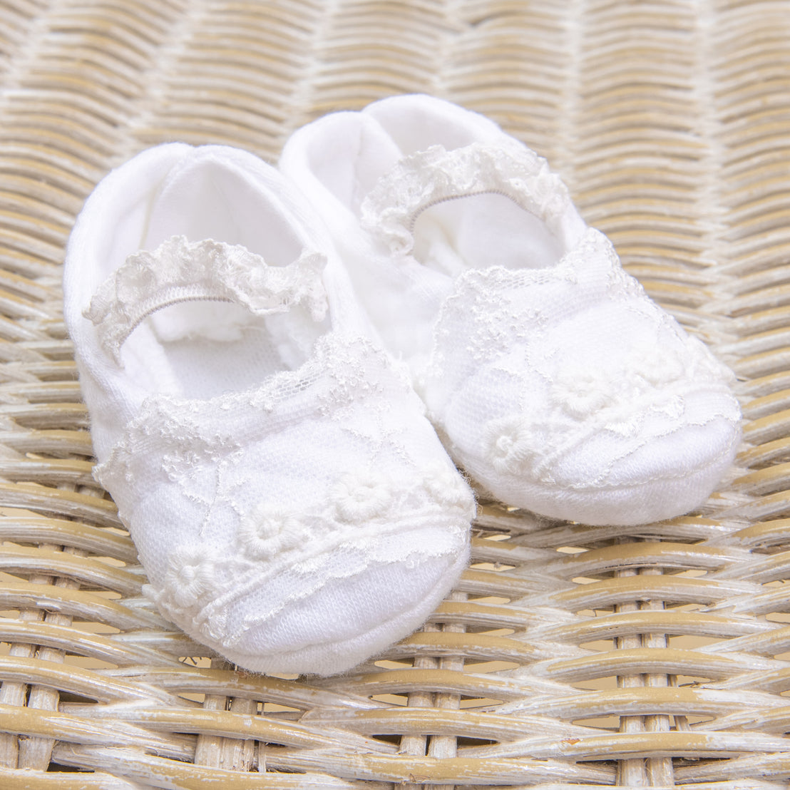 A pair of Eliza Booties with delicate lace detailing, perfect for a christening.