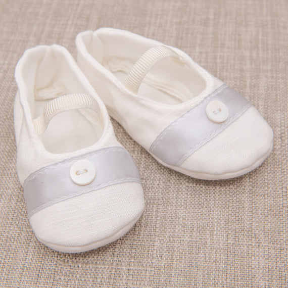 A pair of baptism booties pictured on chair.