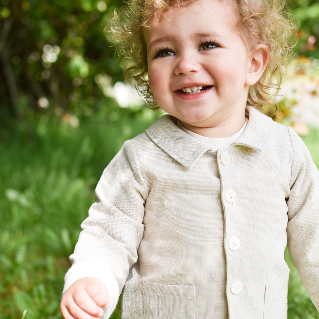 Baby boy in a forest wearing the tan Silas Trench Coat