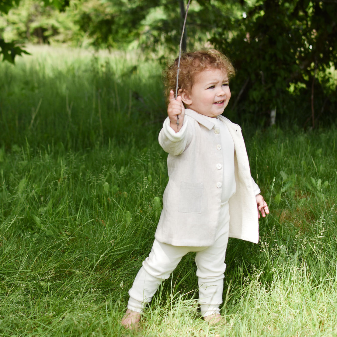 Baby boy out in the forest wearing the tan Silas Trench Coat