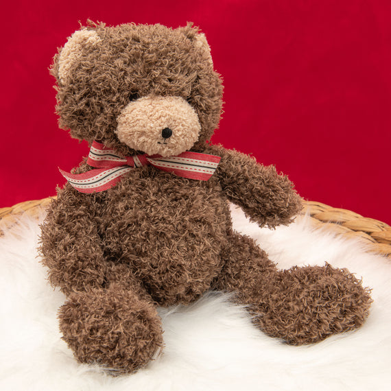 A photo of the Cubby Bear, a soft stuffed animal bear, sitting on a white fur rug.