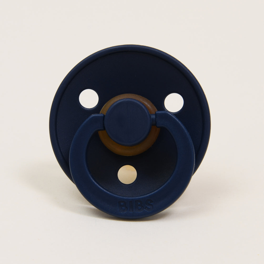 A navy blue Bibs Pacifier set with a round mouthpiece and a ring handle, featuring three ventilation holes and the upscale brand name "bibs" visible on the front.