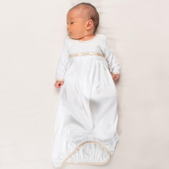 Newborn baby boy wearing the Liam Cotton Newborn Gown crafted from soft white pima cotton, ivory quilted cotton bodice, and detailed with silk trim in a shade of champagne