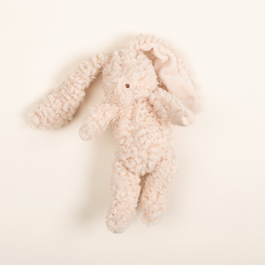 Harey Bunny, a plush with long ears and soft cream-colored fur, rests on a plain white background. One of its ears is slightly folded over, adding a whimsical touch. This cuddly companion is the perfect baby gift or bunny friend for any little one.