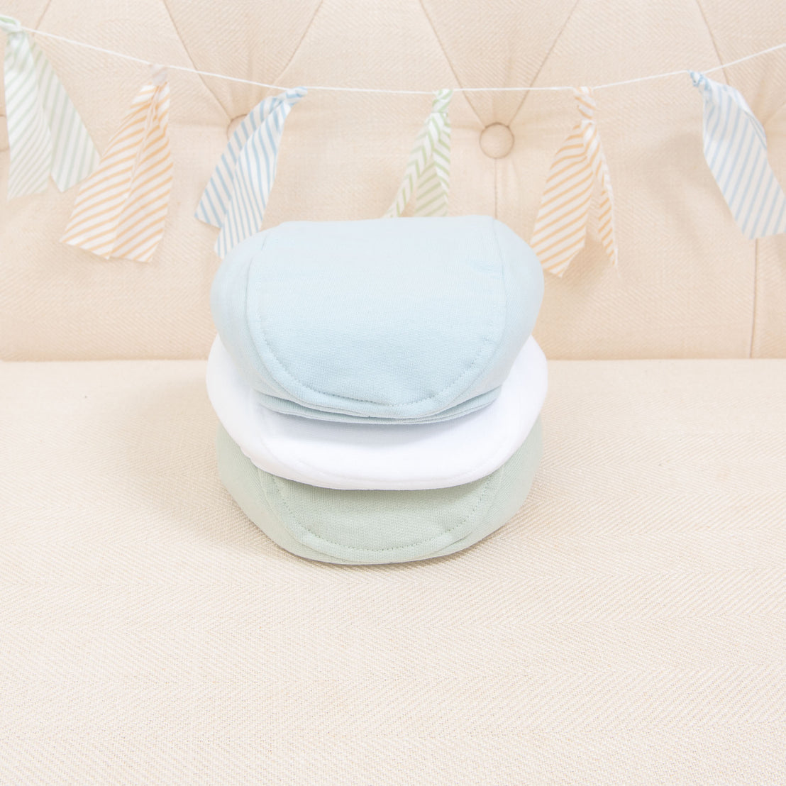 Flat lay photo of the the three Theodore Newsboy Caps in blue, green, and white.