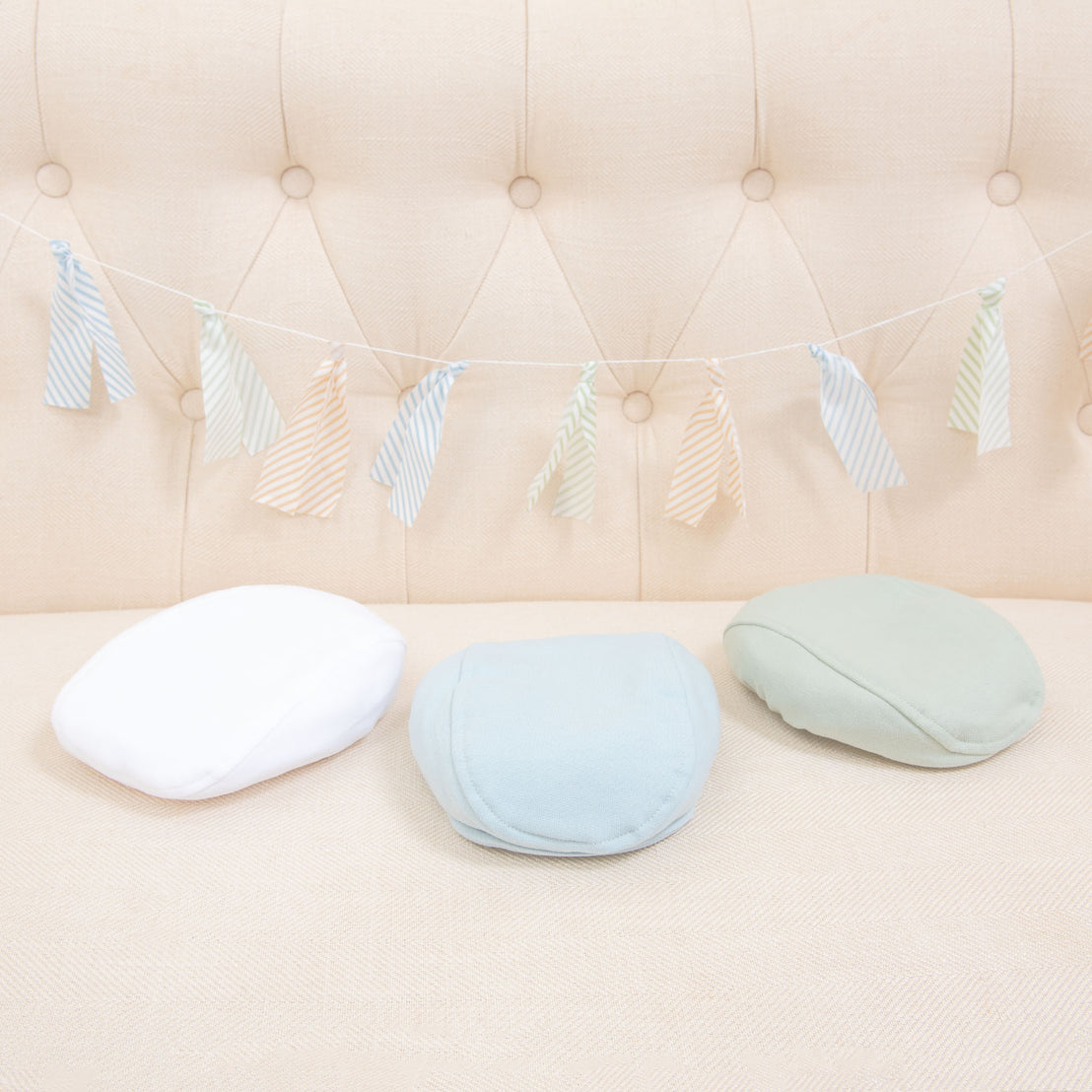 Flat lay photo of the the three Theodore Newsboy Caps in blue, green, and white.