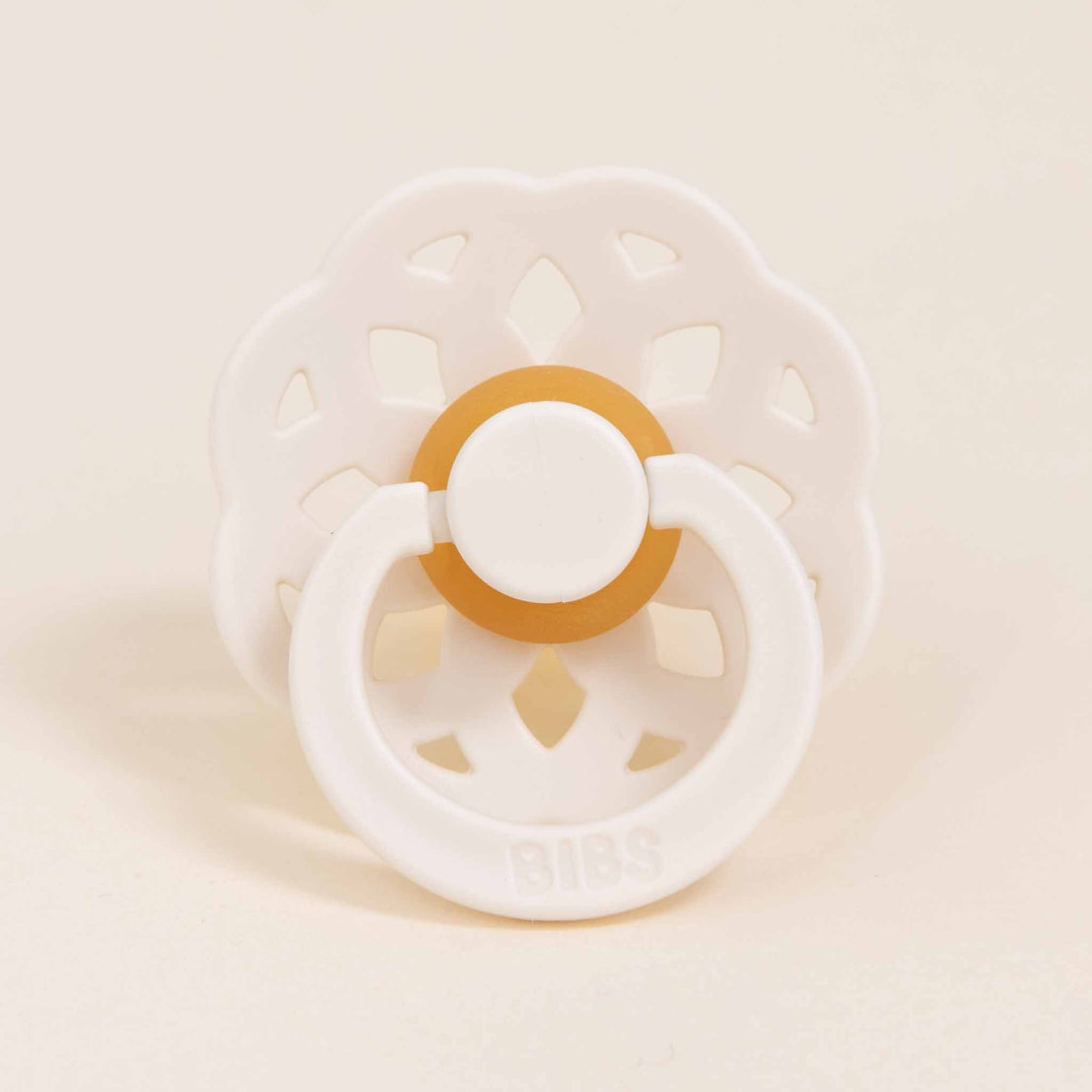 A close-up flat lay photo of the ivory pacifier from the Ella Pacifier Set.