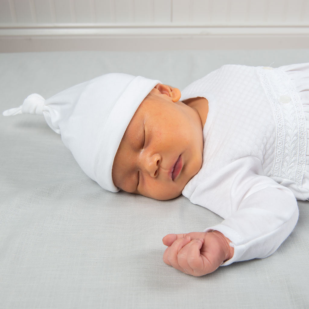 Close up detail photo of baby wearing the Elijah Newborn Gown and Hat. The photo features the pima knot hat