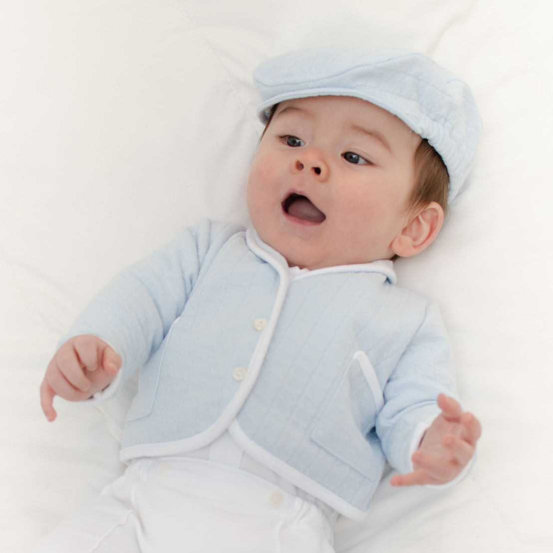 Baby boy laying on the ground and wearing the Logan 3-Piece Suit, including the jacket, pants and onesie (and matching Logan Newsboy Cap).