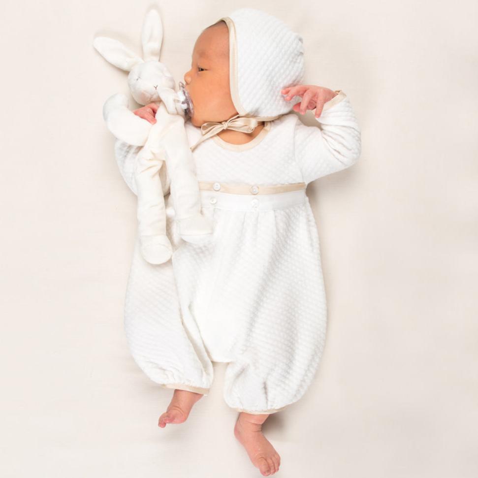 Photo of a newborn baby wearing the Quilted Newborn Romper and holding a stuffed animal bunny