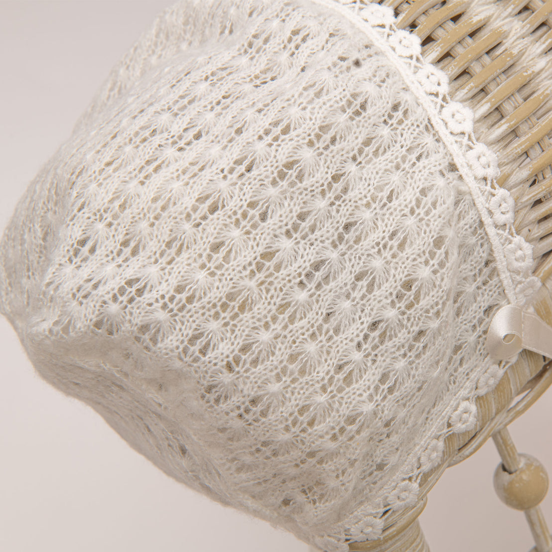 A flat lay photo of the Ella Knit Bonnet hanging from a wicker chair.