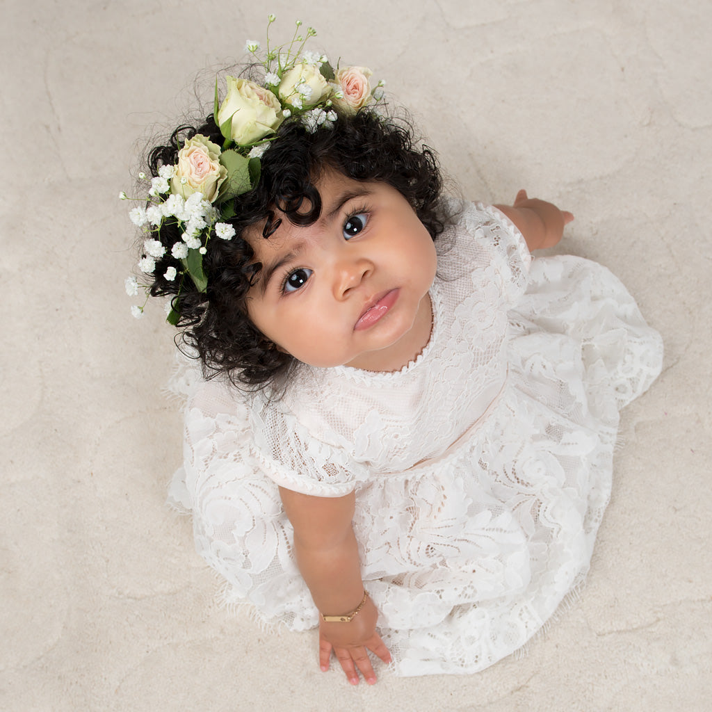 Baby girl wearing the pink Victoria Puff Sleeve Christening Dress. The dress is lined with rich silk Dupioni in a vintage pink champagne color which enhances the gorgeous embroidered ivory lace that falls over top.