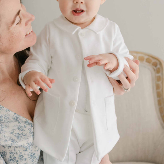 Baby boy with his smiling mother. He is wearing the Miles Trench Coat over the Miles Suit.