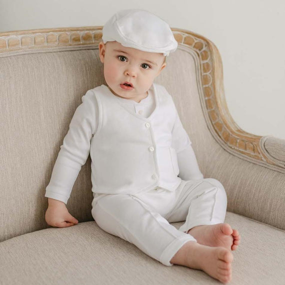 Baby boy sitting on a chair wearing the Miles vest Suit and Newsboy Cap made with french terry in white