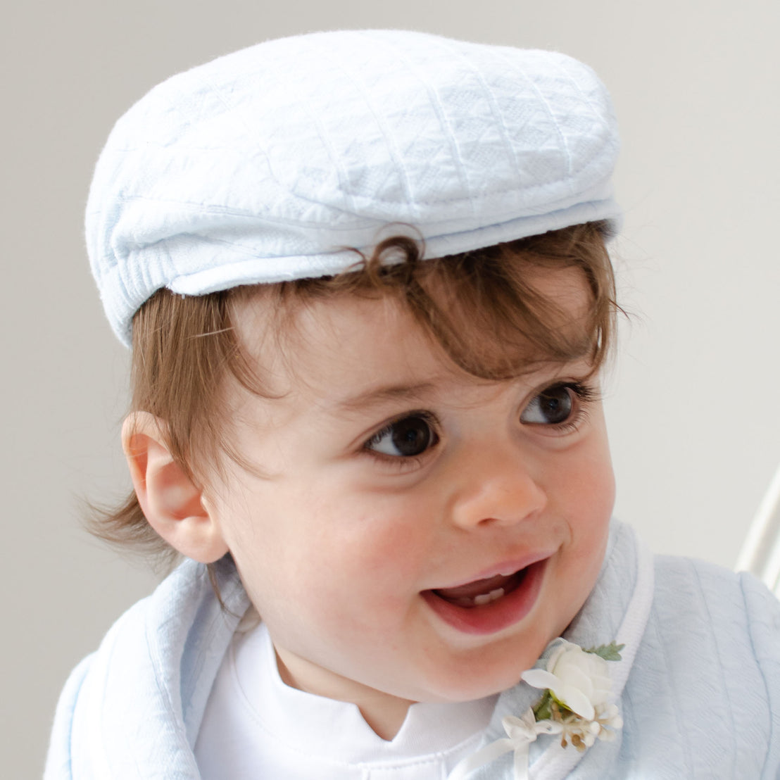 Baby boy smiling and wearing the Logan Newsboy Cap. 