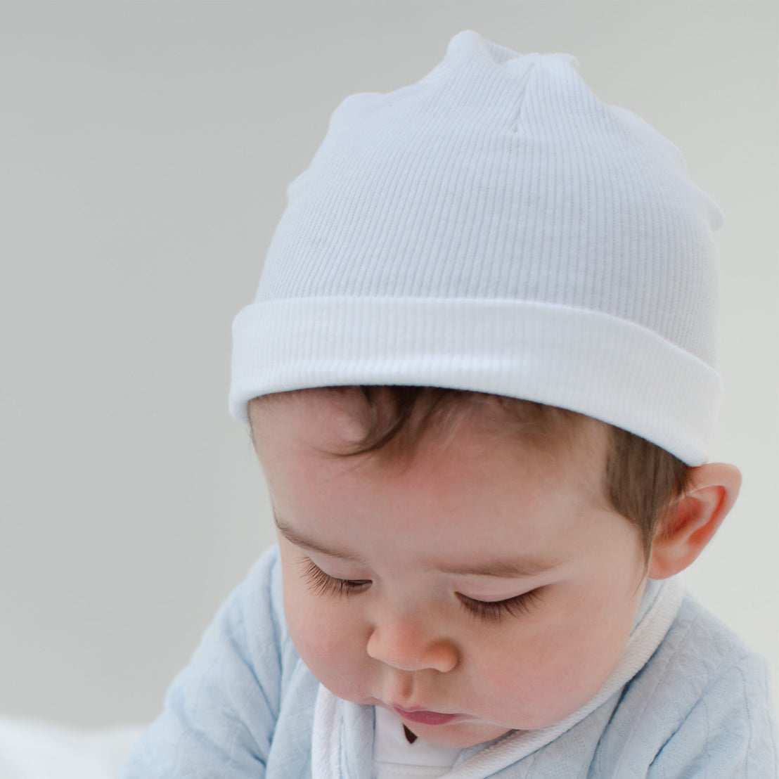 Baby boy wearing the White Ribbed Cotton Beanie made from 100% ribbed textured cotton.