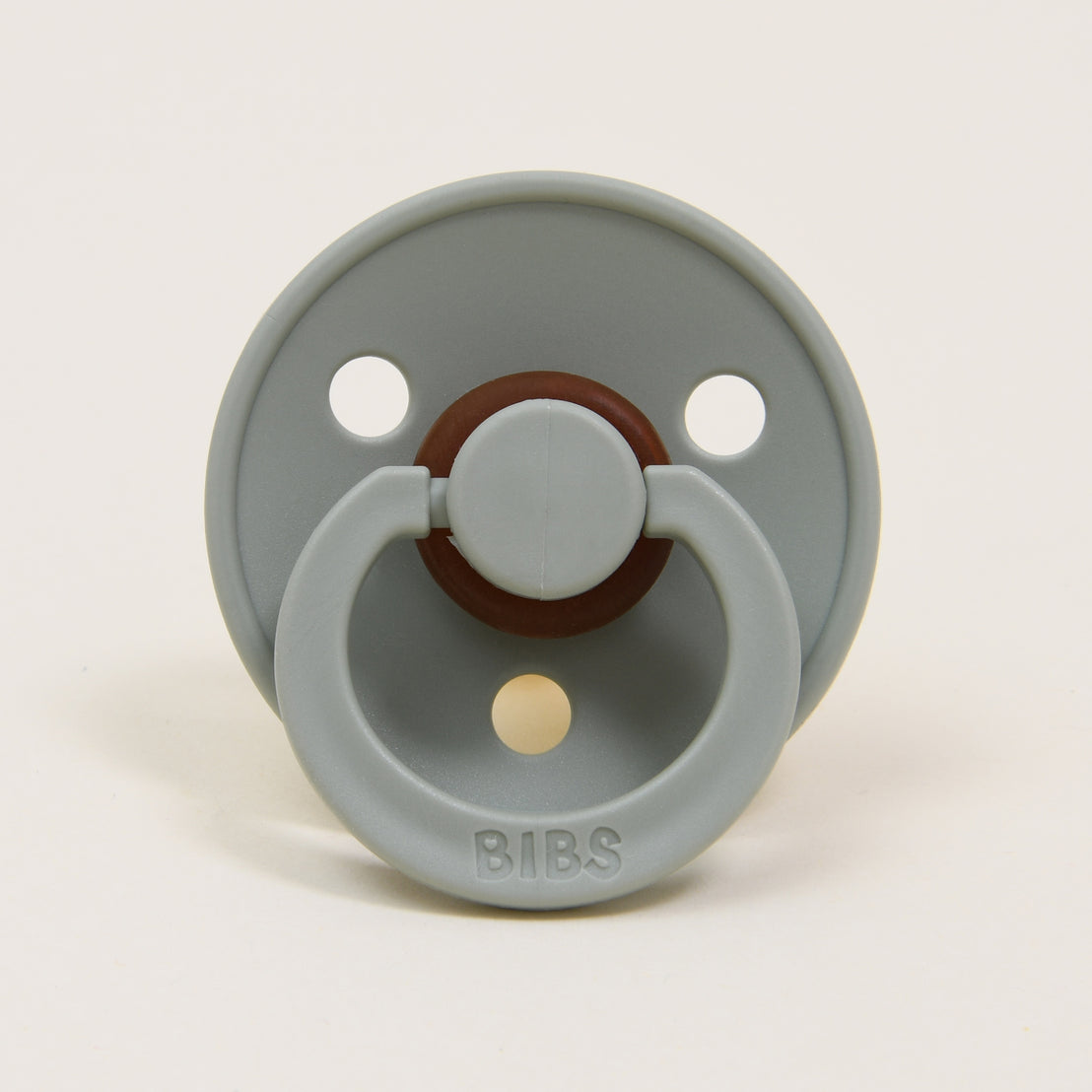 A Bibs Pacifier in "sage" color featuring a brown button handle and a tan nipple, displayed against a plain white background.