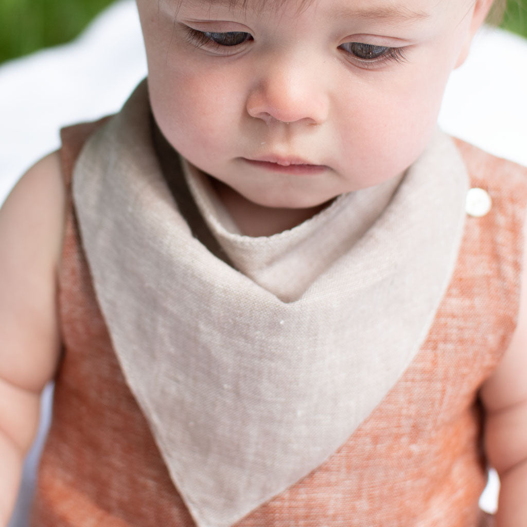 Baby boy wearing the sand colored Silas Bandana Bib