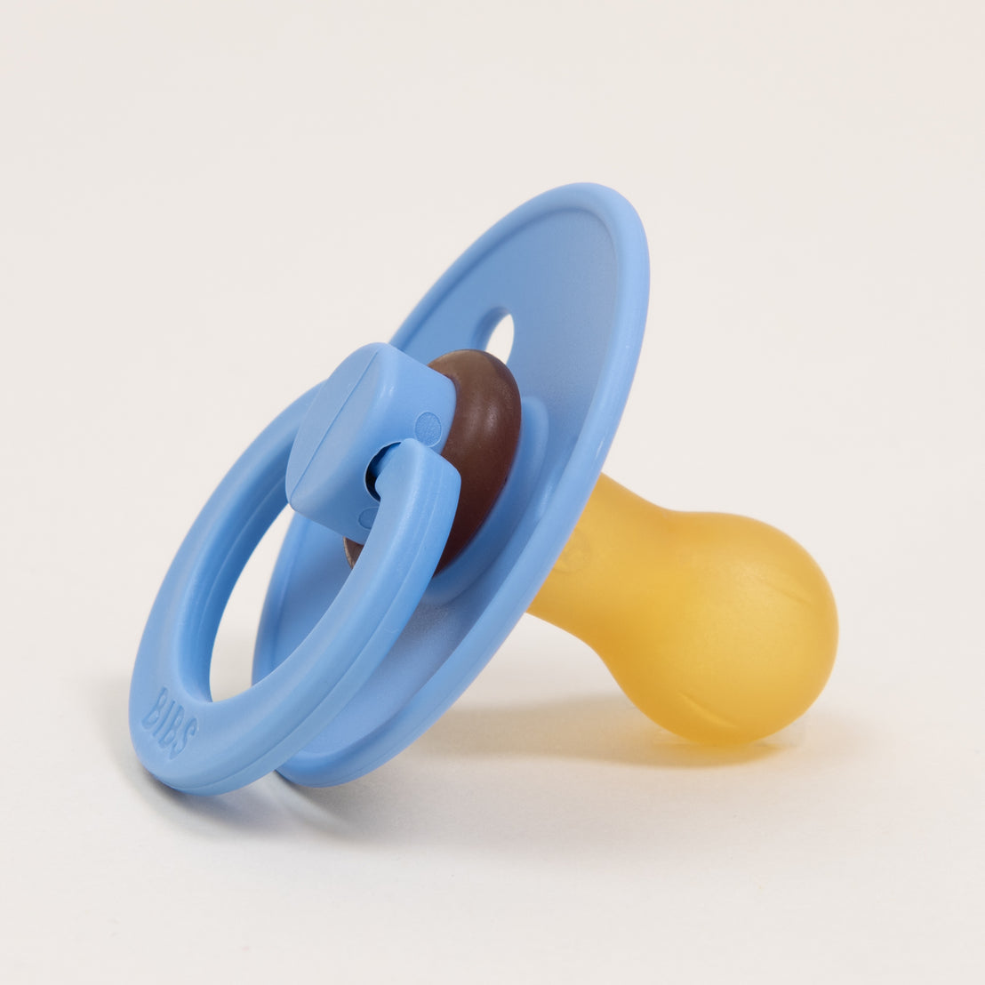 A natural Sky Blue and yellow baby pacifier with a round handle, isolated on a white background.