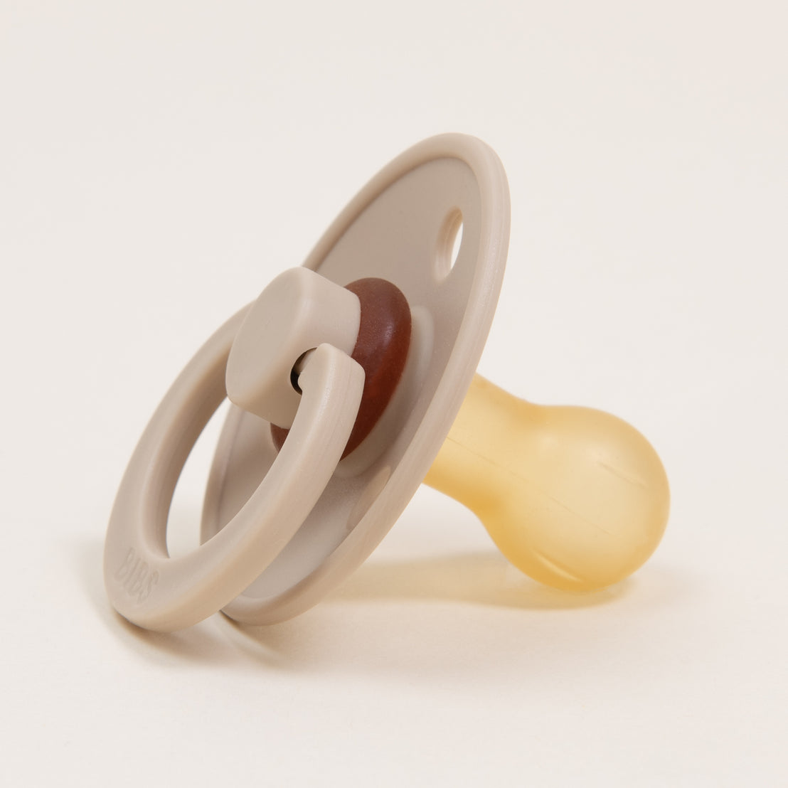 A close-up image of the Ian Pacifier Set with a tan shield, brown handle, and clear silicone nipple, designer-inspired, isolated on a white background.